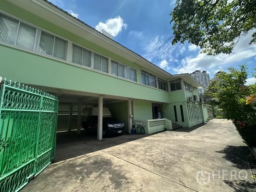 Retail Space for rent in Watthana, Bangkok - Two-storey light-green standalone building with wide driveway and covered parking.