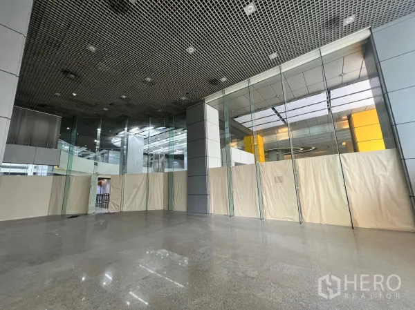 Retail Space for rent in Watthana, Bangkok - Open-plan retail space featuring expansive glass walls and a modern grid ceiling inside a commercial tower lobby.