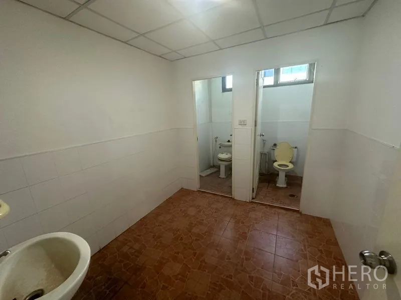 Warehouse for rent in Saphan Sung, Bangkok - Restroom with two cubicles, tiled floor and basin.