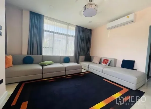 独立式住宅 出售在Sai Mai, Bangkok - 采光充足的客厅，超大转角沙发、窗帘与空调。