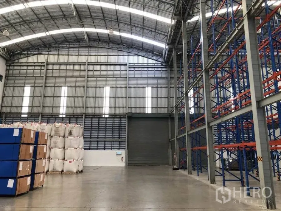 Warehouse for rent in Bang Pakong, Chachoengsao - High-bay warehouse interior with arched roof, skylights, roller shutter door, pallet racks and polished concrete floor.