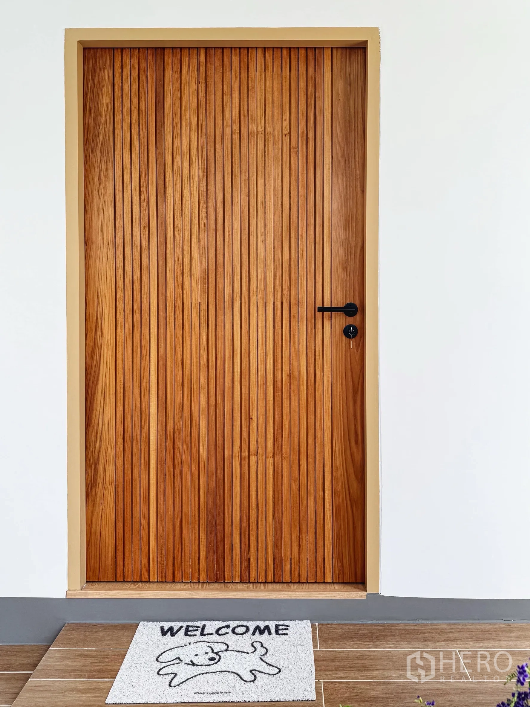 Detached House for sale in Suan Luang, Bangkok - Close-up of the vertical slat wooden front door with a welcome mat.