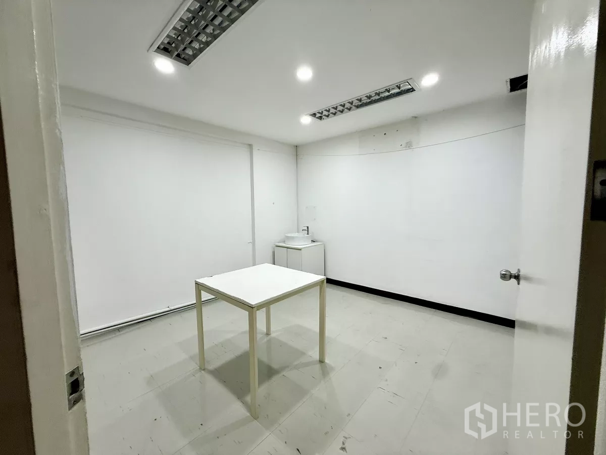 Office Space for rent in Din Daeng, Bangkok - Bright office room with table, fluorescent light panels and a small sink cabinet.