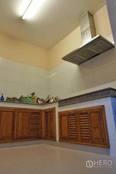 Detached House for rent or sale in Pak Kret, Nonthaburi - Separate Thai kitchen with wooden base cabinets, tiled backsplash and stainless-steel range hood.