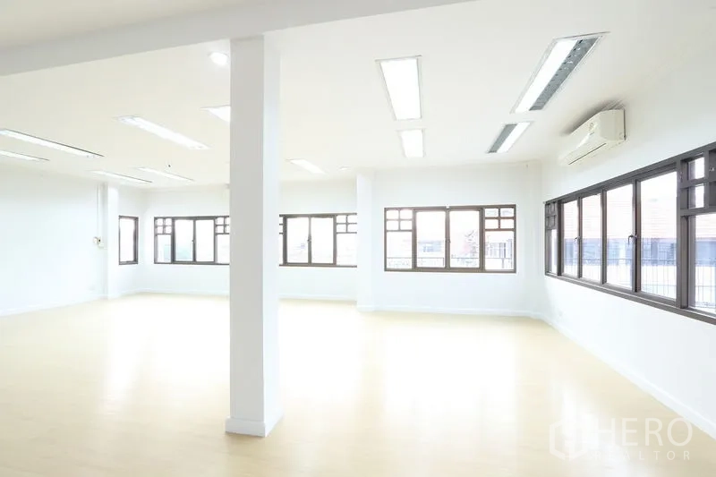 Office Space for rent in Bang Na, Bangkok - Corner office room with wood floors, air‑conditioning and wraparound windows providing daylight.