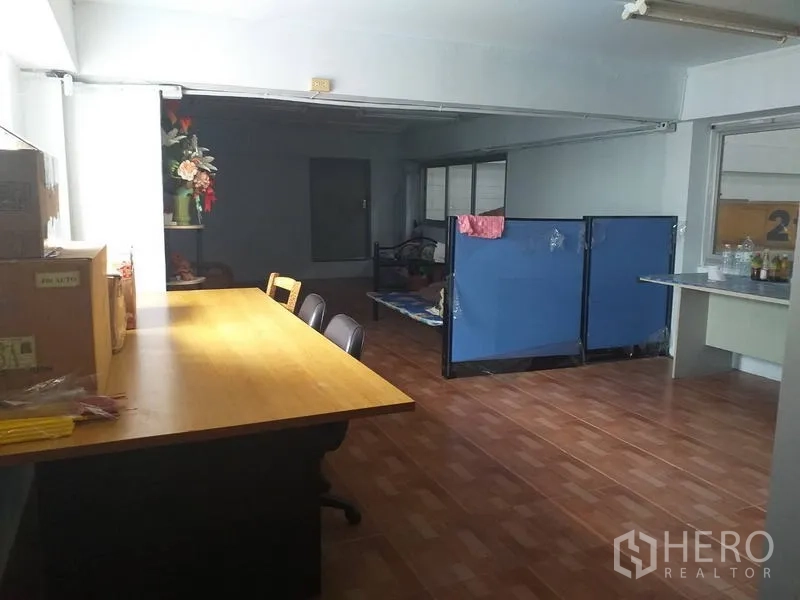 Factory for sale in Khlong Luang, Pathum Thani - Large multipurpose room with wooden flooring, long table and partition screens.