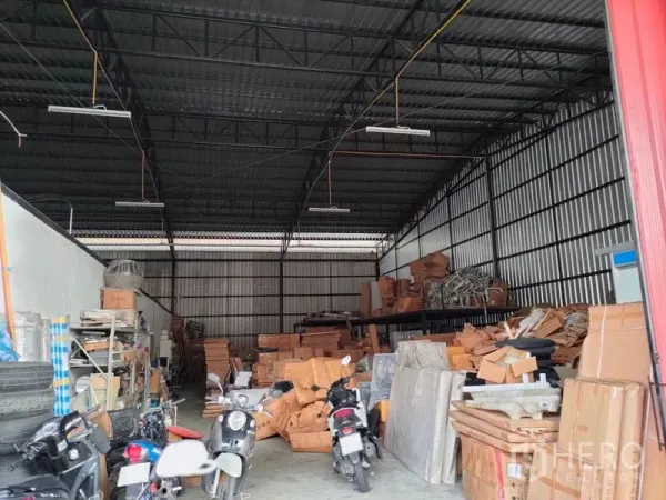 Warehouse for rent in Bang Kapi, Bangkok - High-ceiling steel-frame warehouse interior with shelving, stacked boxes, and overhead lighting.