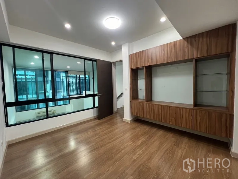Townhouse for rent or sale in Khlong Toei, Bangkok - Multipurpose room with a wood built-in TV wall and interior glass windows.
