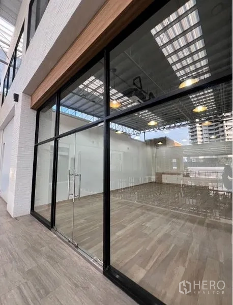 Retail Space for rent - Street‑facing retail unit with full‑height glass storefront and wood‑look tile flooring under a covered walkway.