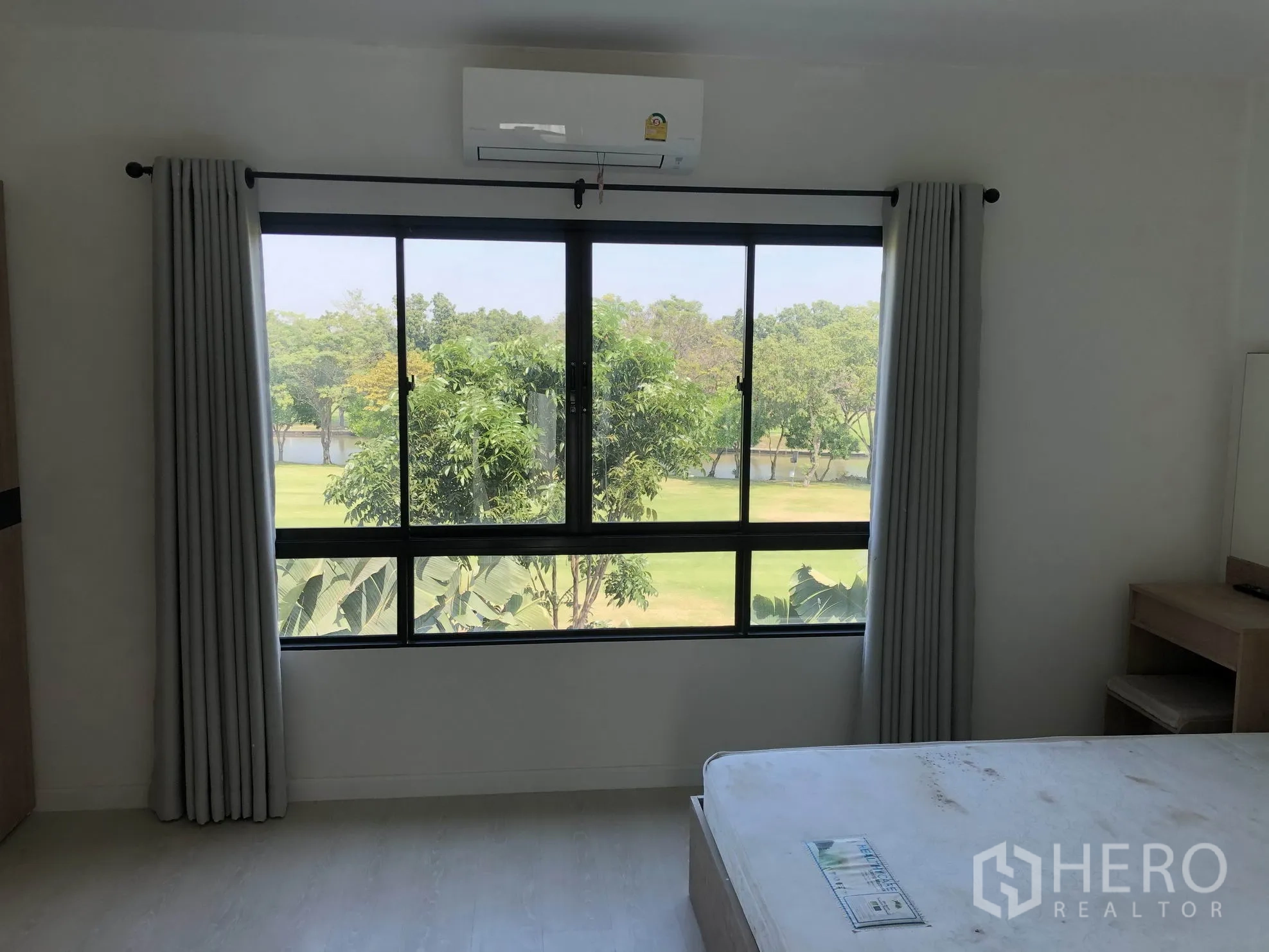 Townhouse for rent in Bang Kapi, Bangkok - Master bedroom window framing lush park and lake views with abundant natural light.