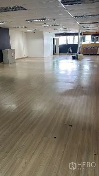 Office Space for rent - Open office area with natural light, columns and a pantry/workbench at the far end.