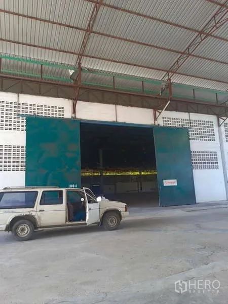 Warehouse for rent in Mueang Rayong, Rayong - Warehouse entrance with wide sliding doors and a vehicle parked outside.