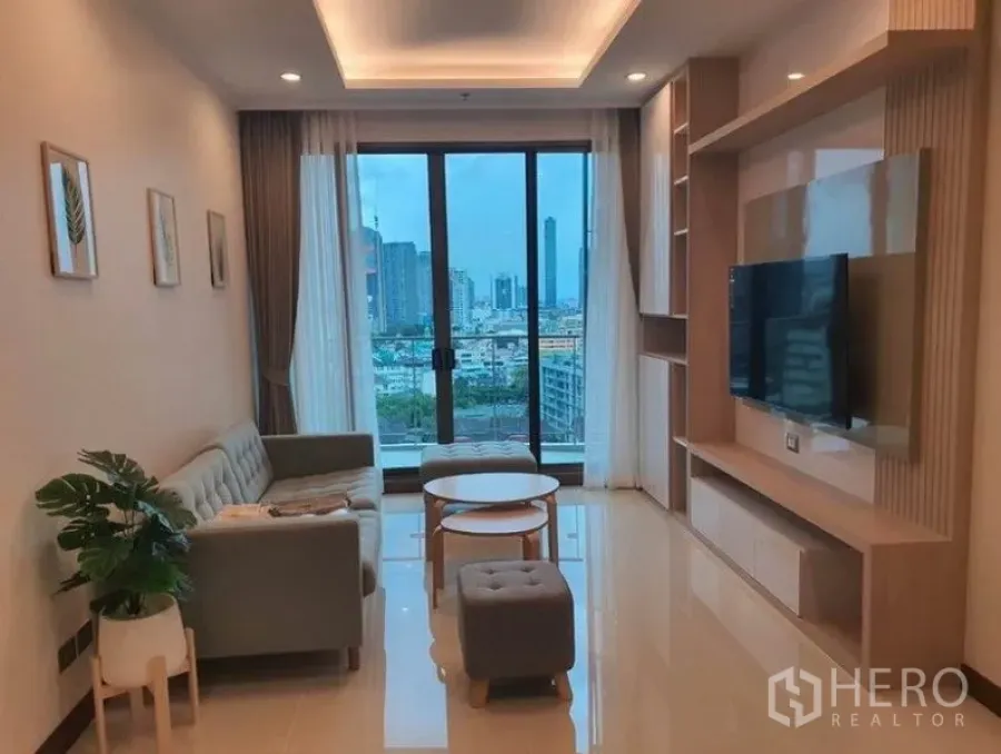 Condominium for rent in Watthana, Bangkok - Bright living room with built-in TV wall, sofa set and floor-to-ceiling windows overlooking the Bangkok skyline.