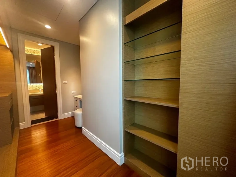 Condominium for rent in Khlong Toei, Bangkok - Hallway with open shelving leading toward a vanity and bathroom entrance.