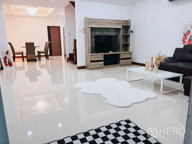 联排别墅 出租在Huai Khwang, Bangkok - 开放式客厅，电视柜、L形沙发与亮面地砖。