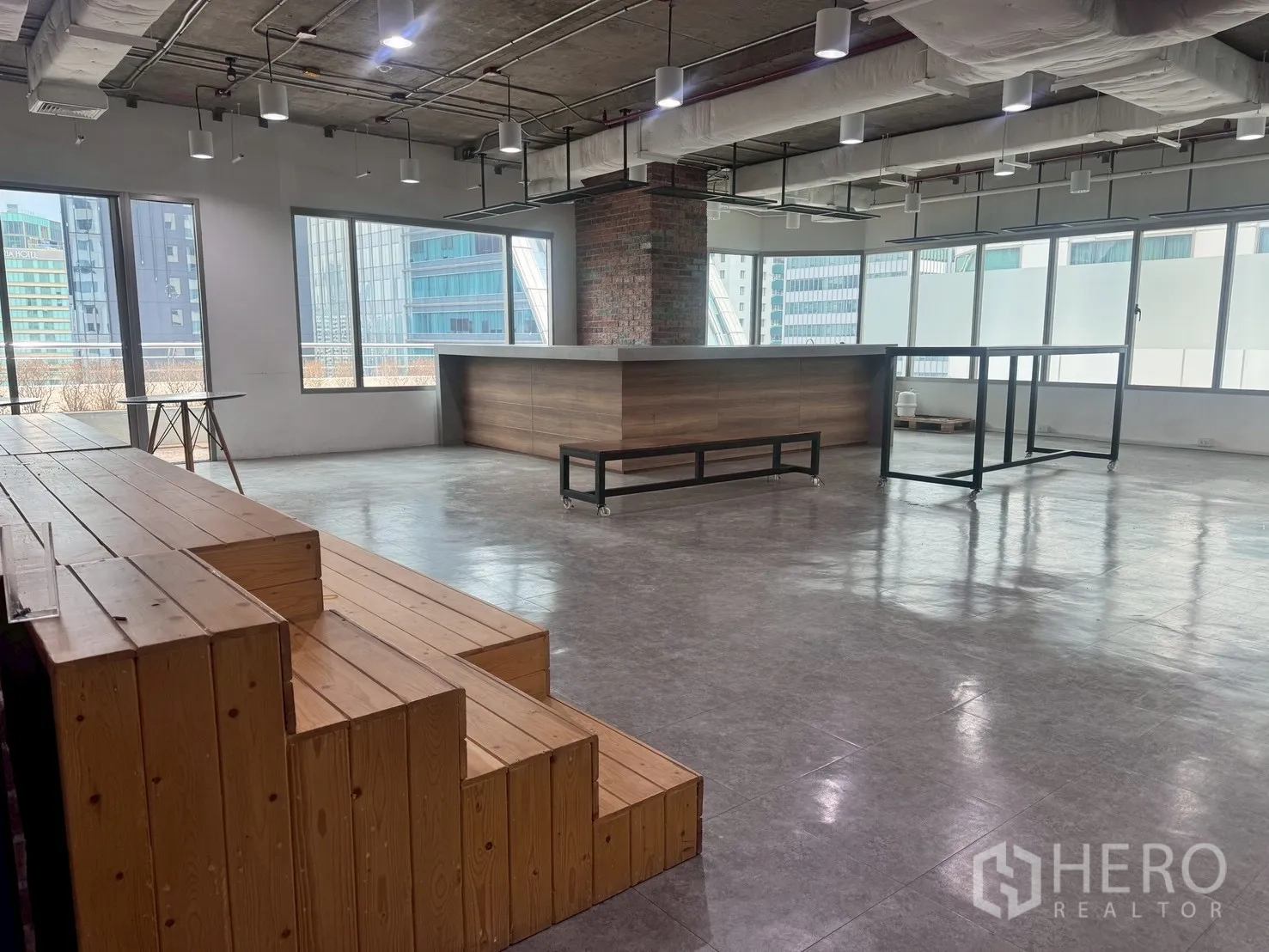 Office Space for rent in Watthana, Bangkok - Communal zone with wooden tiered seating and a long counter beside windows.