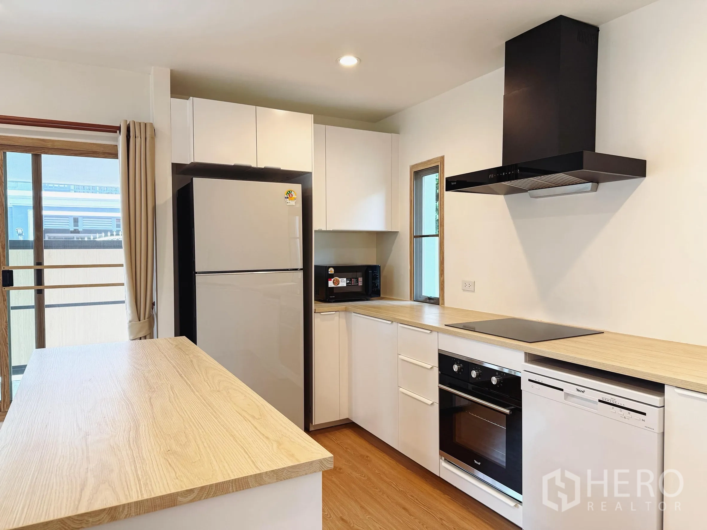 Detached House for sale in Suan Luang, Bangkok - Modern kitchen with island, built-in oven, cooktop, hood and tall fridge.