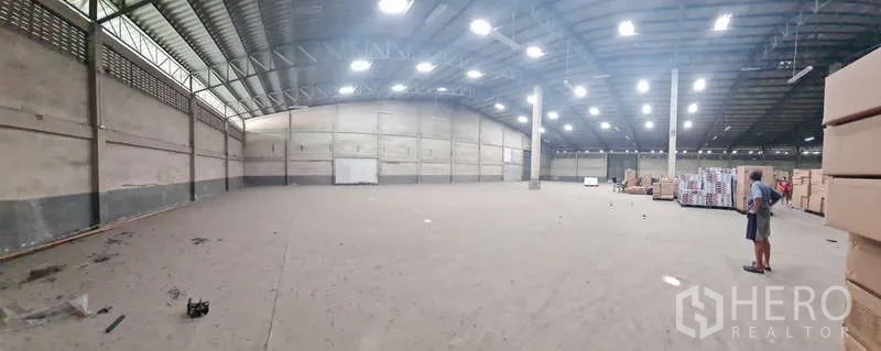 Warehouse for rent - Panoramic view of wide warehouse floor with boxes and central support columns.