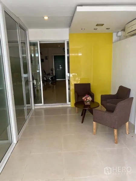 Home Office for rent in Wang Thonglang, Bangkok - Small waiting area with two armchairs, round table and a yellow feature wall.