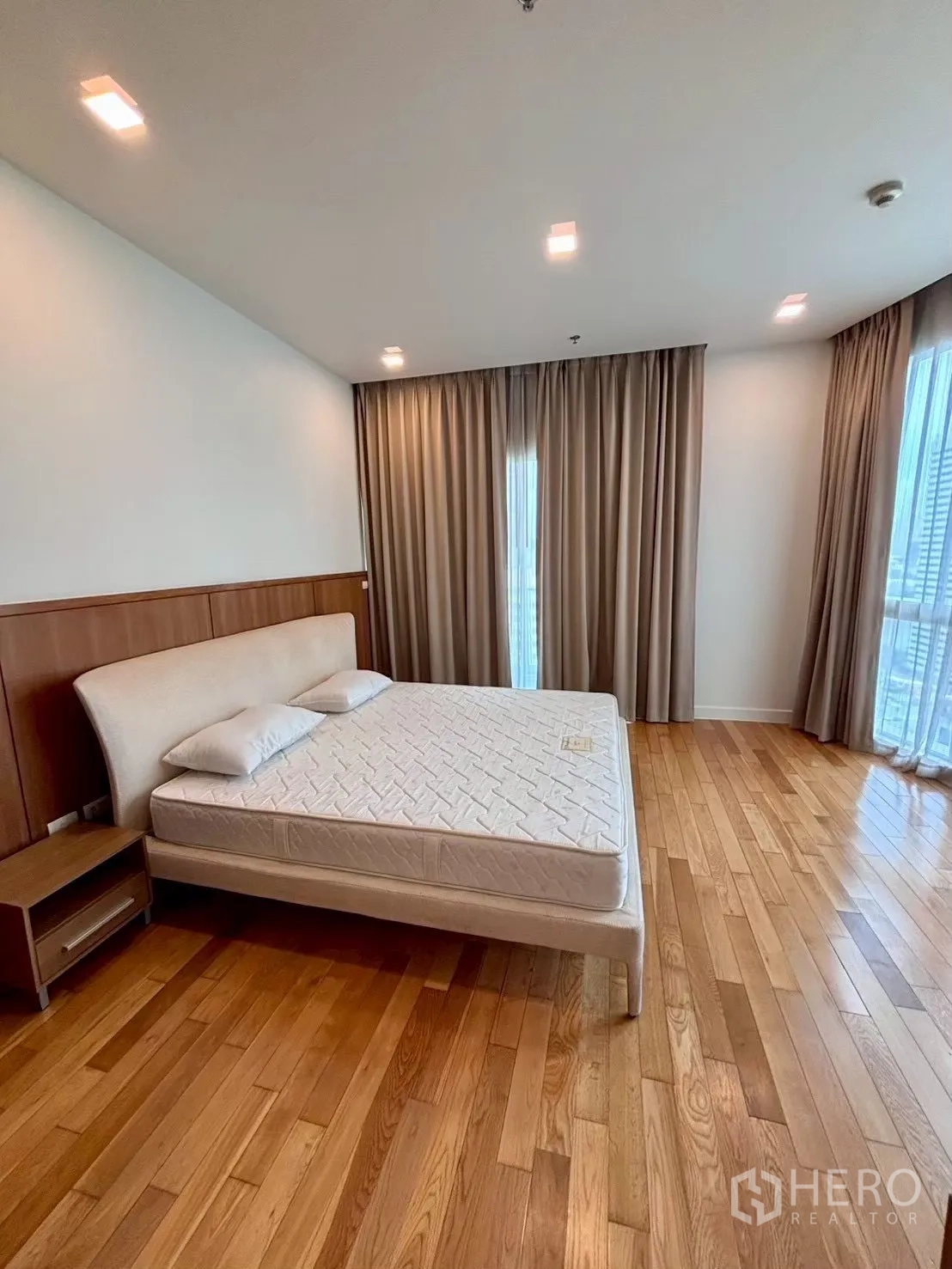 Condominium for rent in Khlong Toei, Bangkok - Master bedroom with corner windows, curtains and king bed
