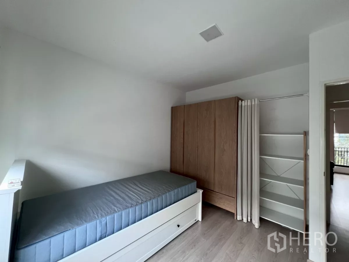 Townhouse for rent in Bang Phli, Samut Prakan - Second bedroom with single bed, wardrobe, and open storage shelves.