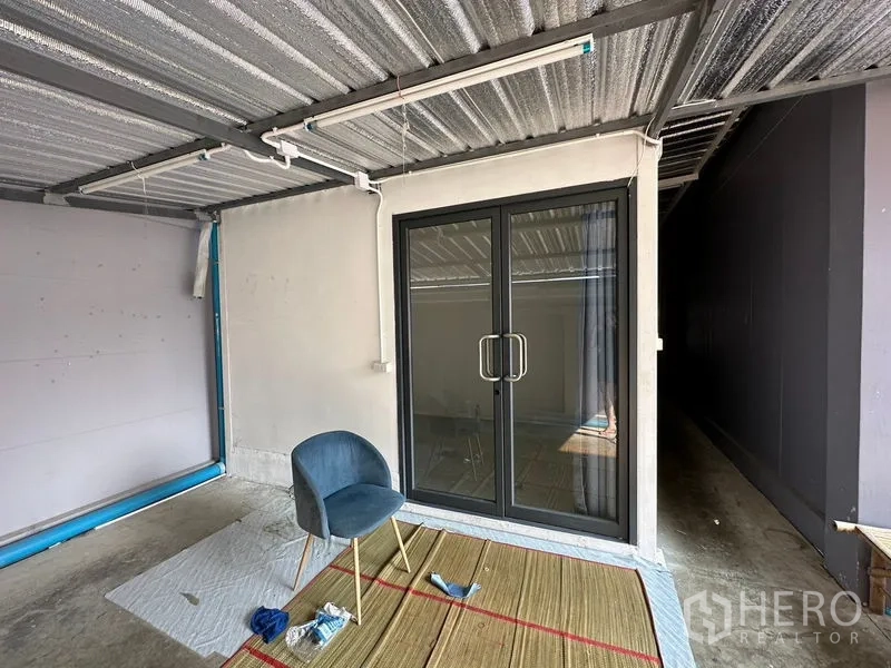 Factory for rent or sale in Lam Luk Ka, Pathum Thani - Covered side area with sliding glass door under a metal roof.