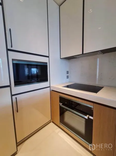 Condominium for rent in Khlong Toei, Bangkok - Sleek compact kitchen with built-in oven, microwave and glossy cabinetry.