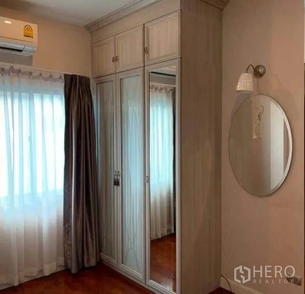 Detached House for sale in Mueang Pathum Thani, Pathum Thani - Bedroom corner featuring a built-in mirrored wardrobe, soft curtains and an air conditioner.