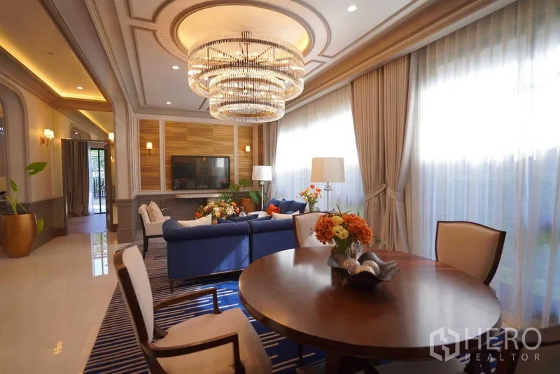 Detached House for sale in Bang Kapi, Bangkok - Family room with coffered ceiling, chandelier, and built-in media wall.