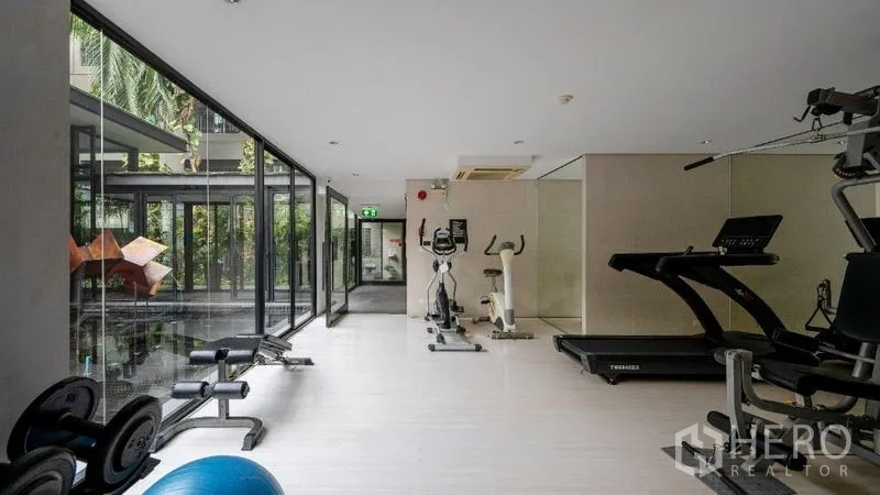 Condominium for sale - Fitness room with treadmills, weights and large windows facing a garden courtyard.