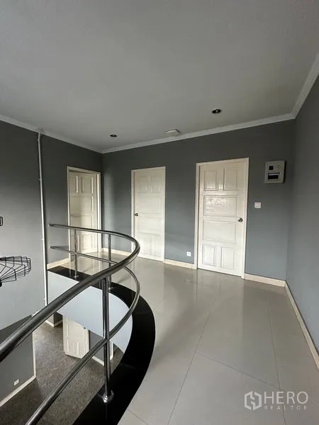 Townhouse for rent in Bang Kapi, Bangkok - Upper landing with metal balustrade and multiple white interior doors.