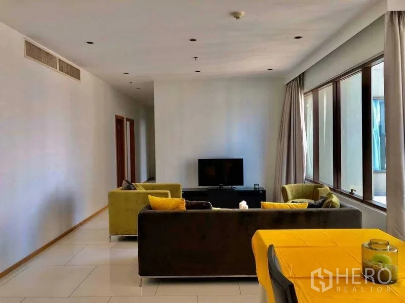 Condominium for sale in Khlong Toei, Bangkok - View from dining toward lounge with corner windows, sofa set and TV console.