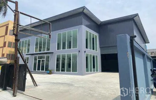 Warehouse for rent in Prawet, Bangkok - Front view of gated warehouse compound showing two-storey office, high roof span, and ample parking apron.