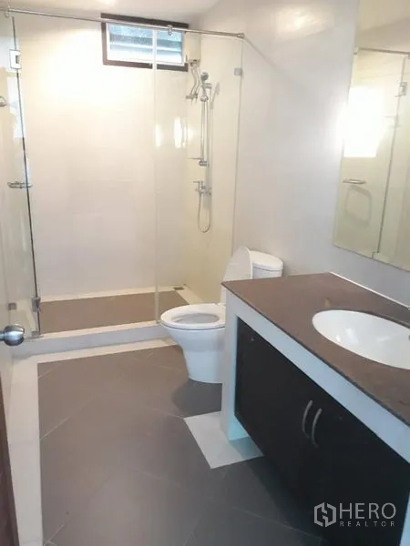 Detached House for rent in Watthana, Bangkok - Modern bathroom with glass-enclosed shower, wide vanity and toilet