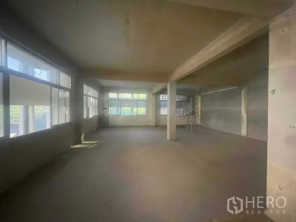 Shophouse for rent in Watthana, Bangkok - Spacious open-plan shophouse floor with concrete columns and large windows.