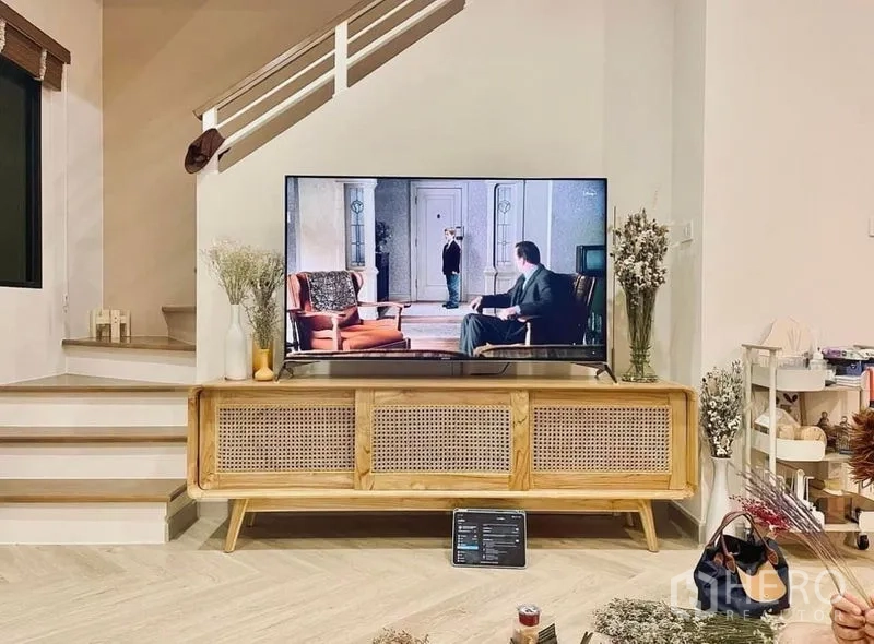 Townhouse for rent in Bang Kapi, Bangkok - TV corner with a wooden console and staircase in a light-toned living room.