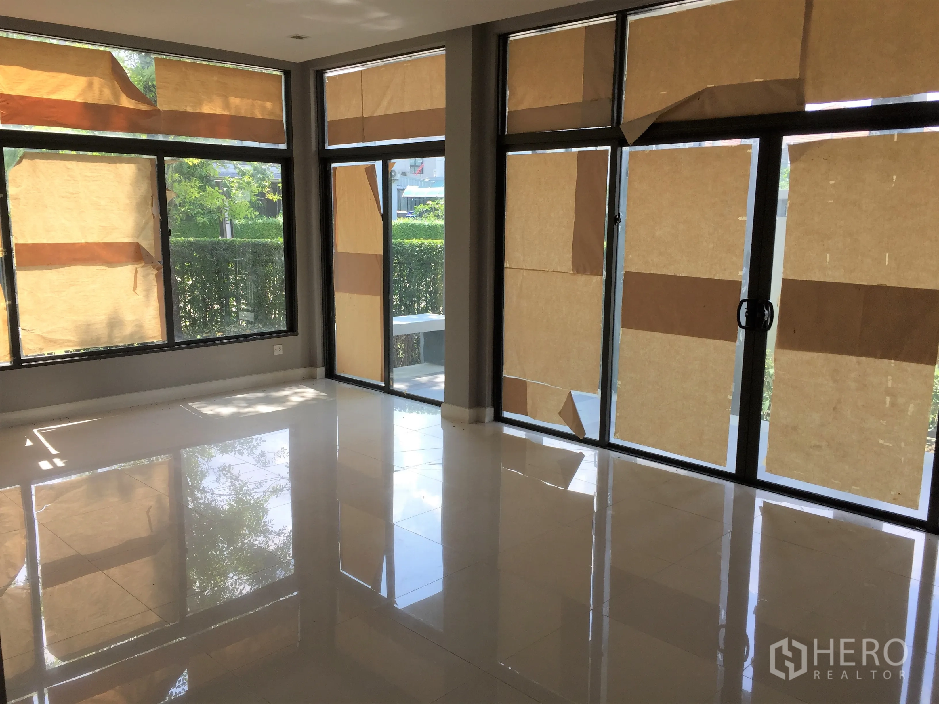 Detached House for rent or sale in Bang Kapi, Bangkok - Bright corner lounge with floor-to-ceiling sliding glass doors opening to the garden.