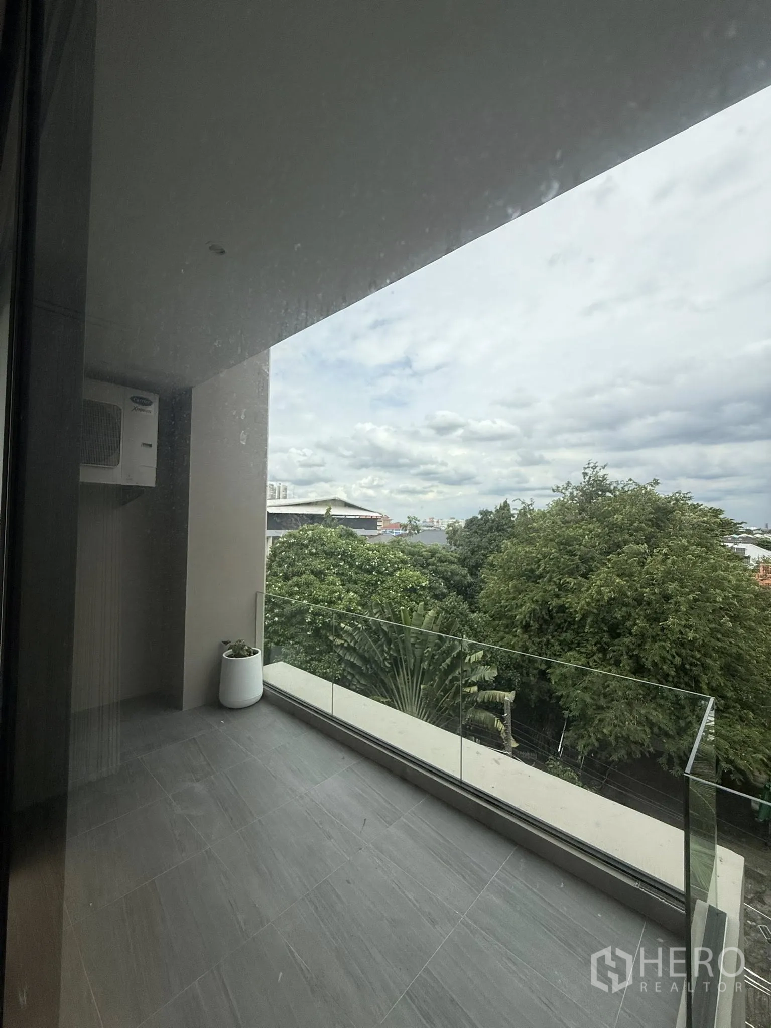 Home Office for rent or sale in Lat Phrao, Bangkok - Covered balcony with clear glass railing and leafy neighborhood views.