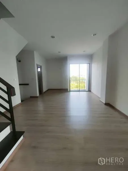 Home Office for rent in Bueng Kum, Bangkok - Upper level room with wood floors, staircase, recessed lighting, and a balcony through sliding glass doors.