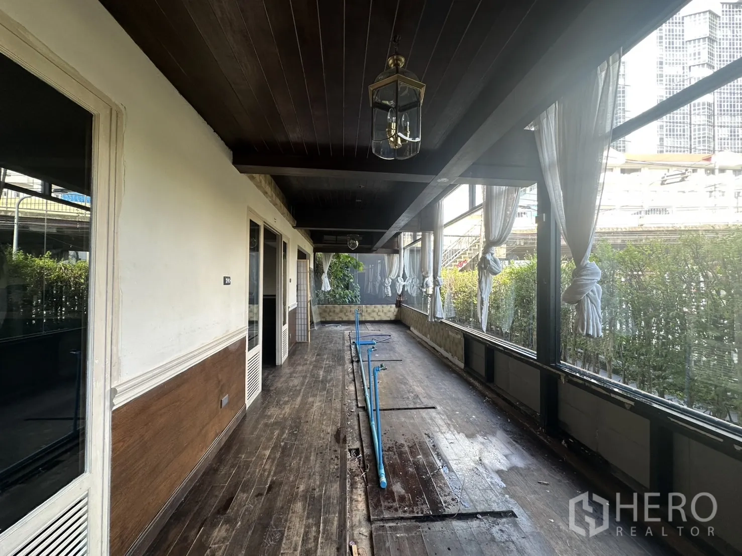 Detached House for rent - Enclosed veranda with tied sheer curtains and city buildings in view.