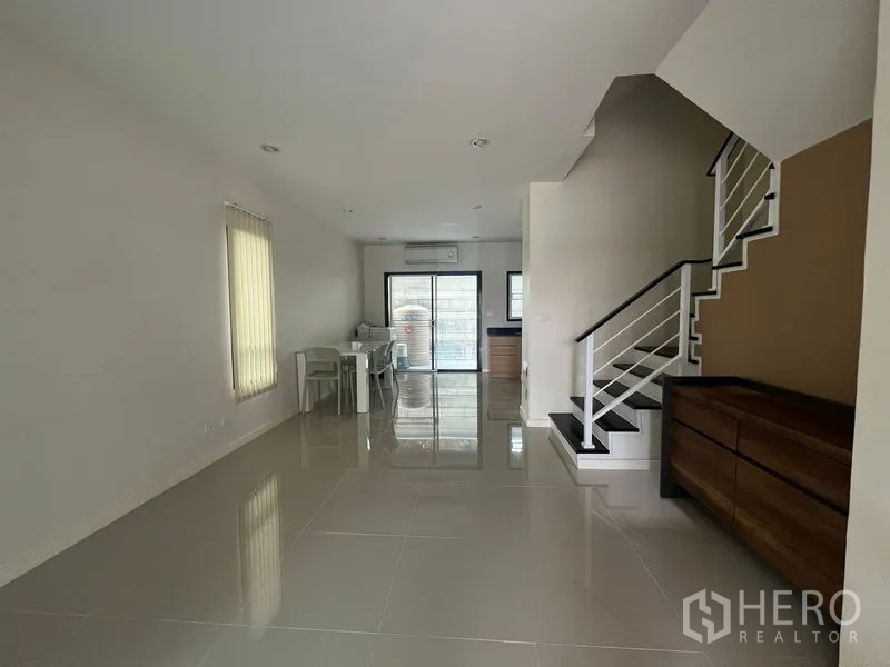 联排别墅 出租在Bang Kapi, Bangkok - 开放式客餐区，亮面地砖与通往楼上的楼梯。
