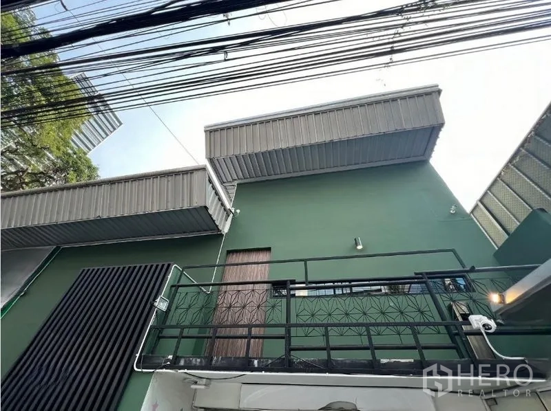 Retail Space for rent in Watthana, Bangkok - Contemporary green retail building with metal awnings, balcony railing and street cables.