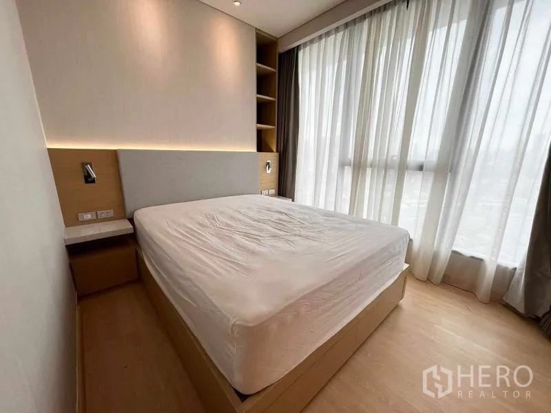 Condominium for rent or sale - Bedroom with floor-to-ceiling windows, sheer curtains, LED headboard, and filtered city light.