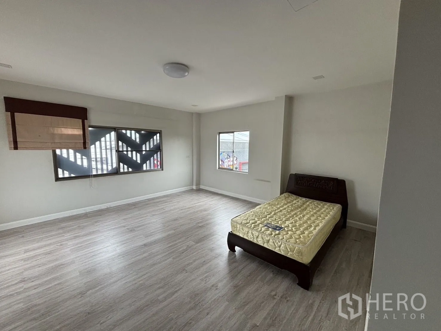 Warehouse for rent or sale in Wang Thonglang, Bangkok - Large bedroom with bed frame, windows and laminate floors.