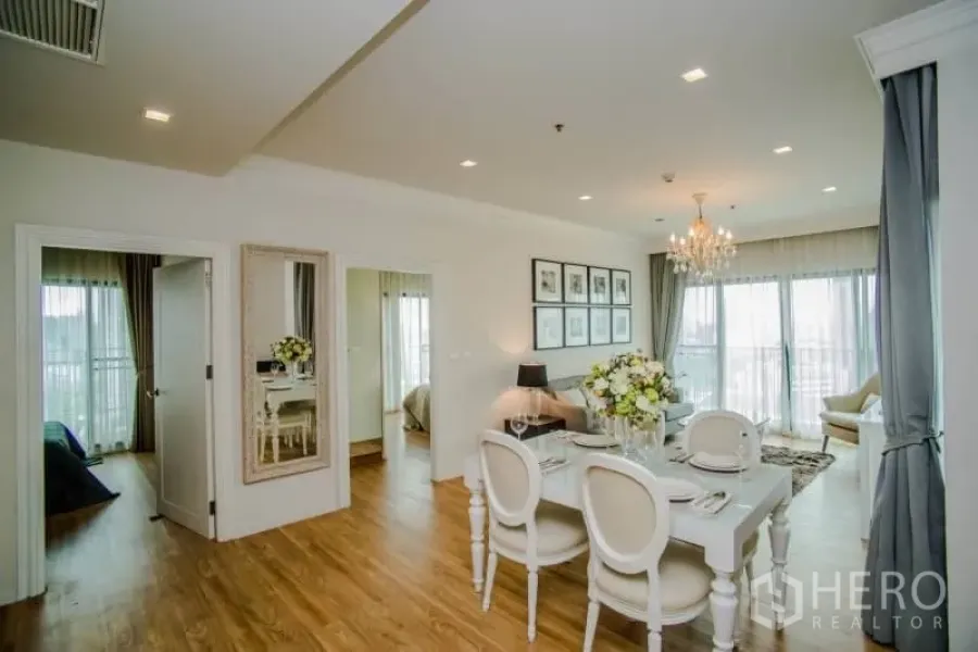 Condominium for rent or sale in Watthana, Bangkok - Open-plan living and dining area with chandelier, wood flooring, and floor-to-ceiling windows.