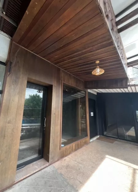 Retail Space for rent - Corner view of wood façade retail entrance beneath a canopy and pendant light.