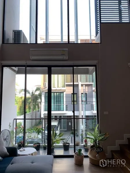 ทาวน์เฮาส์ ให้เช่าในKhlong Toei, Bangkok - ห้องนั่งเล่นเพดานสูงสองชั้น พร้อมกระจกเต็มผนังและวิวระเบียง