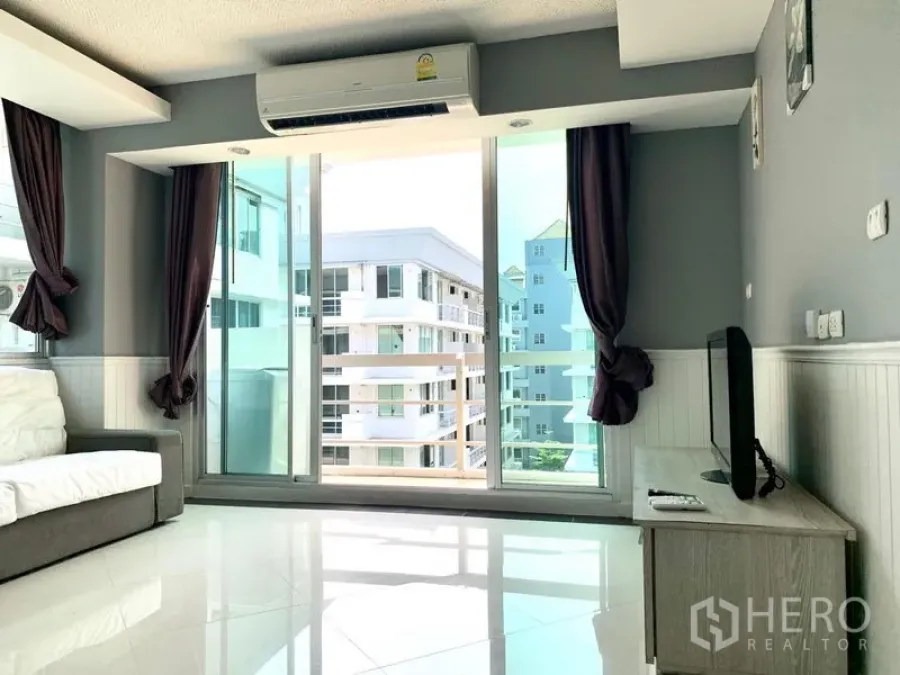 Condominium for rent in Khlong Toei, Bangkok - Living area with sliding glass doors opening to a balcony and city views.