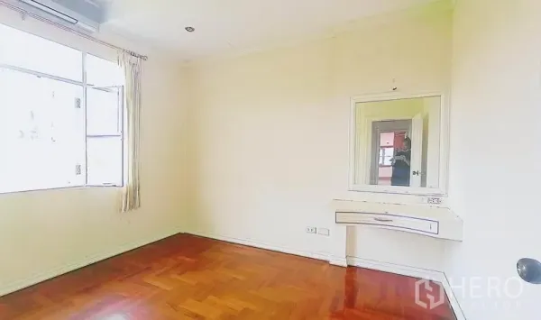 Detached House for sale in Bang Kapi, Bangkok - Sunlit bedroom with parquet floor, large window and built-in vanity.