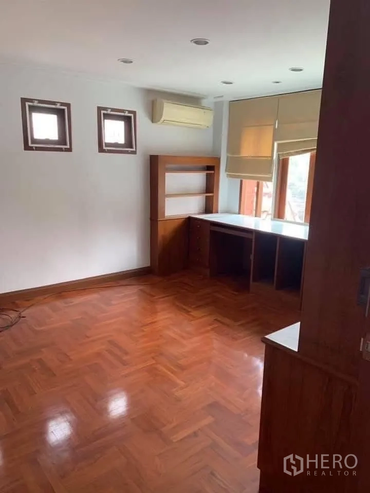 Townhouse for rent in Watthana, Bangkok - Room with built-in wooden desk and shelves, parquet flooring and air conditioner.
